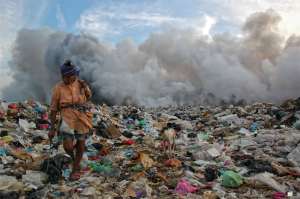 Entre un mar de basura con el  fondo lleno  de humo y acompañada de su fiel mascota esta pepenadora busca algo que le pueda servir. (Foto Alberto Ramos)
