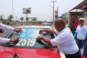 Juan Aldana, de Nueva Alianza, pegando calcomanías en los taxis.