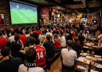 Crowd watching Arsenal versus Tottenham football match in a sports bar