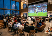 Group of people watching England football match in office with flags and snacks