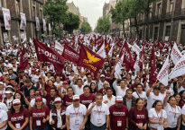 Large Morena political rally filling a city street with flags